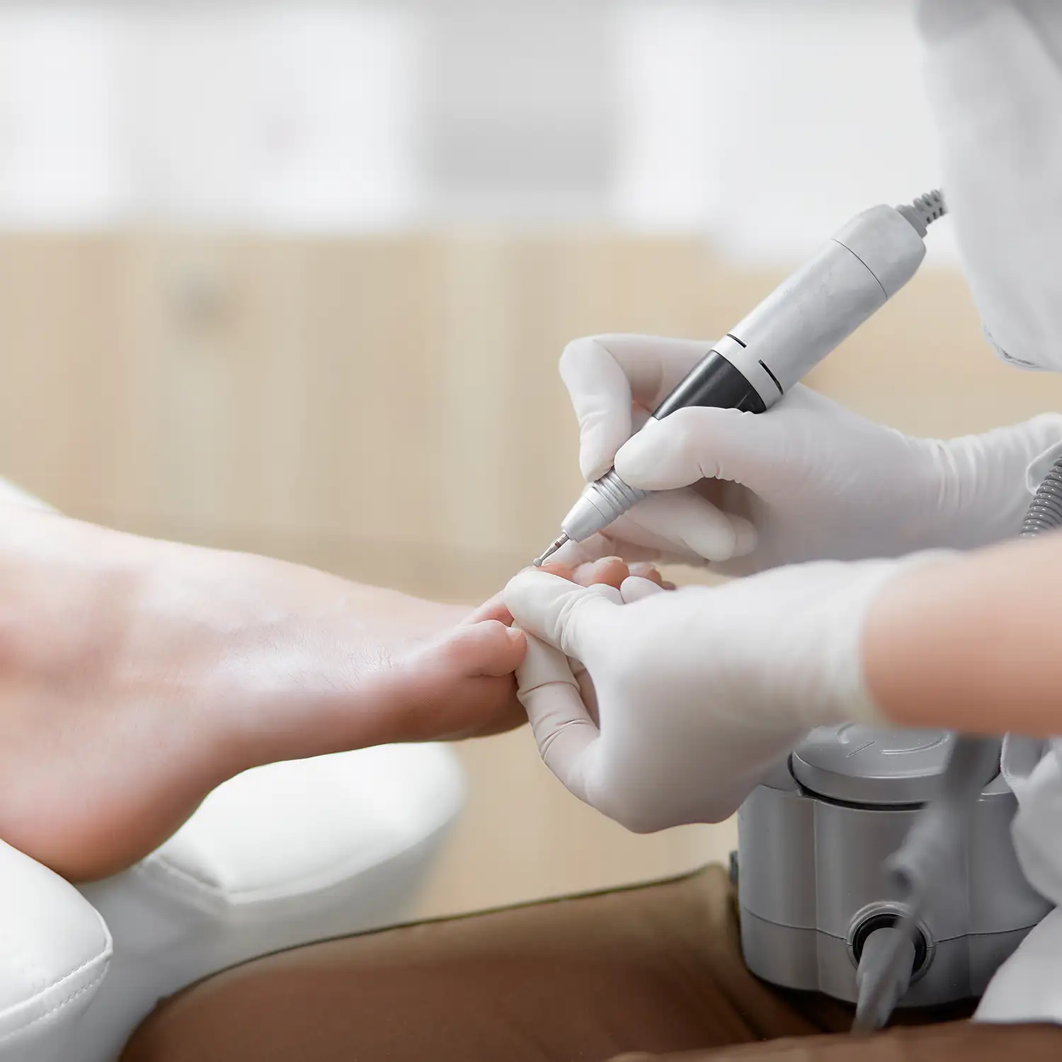 Arzt in Handschuhen bei der Behandlung eines Fußes mit Spezialausrüstung.